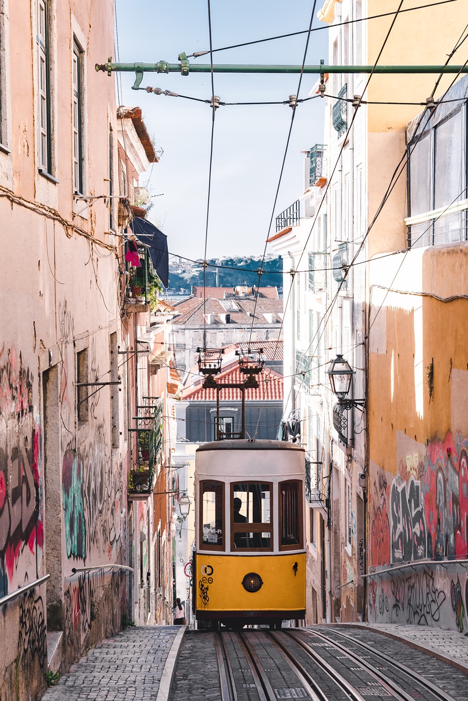 A photo of shot from behind a tram in Lisbon on a narrow city street