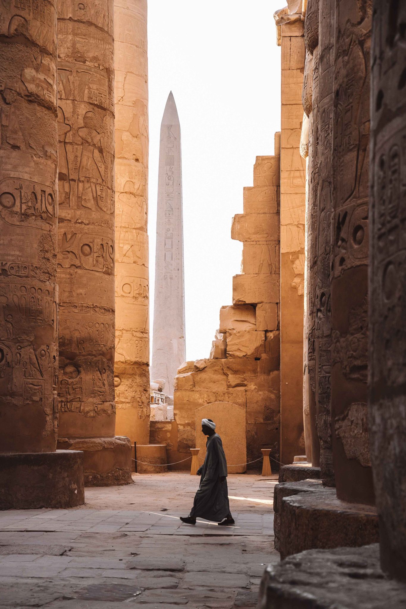 A pretty photo of someone walking in Luxor among the walls of hieroglyphs