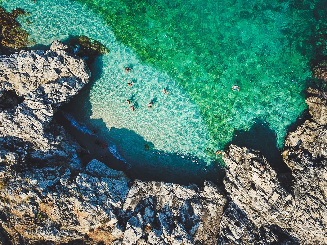 An aerial shot of a rock coast with clear waters in Sicily