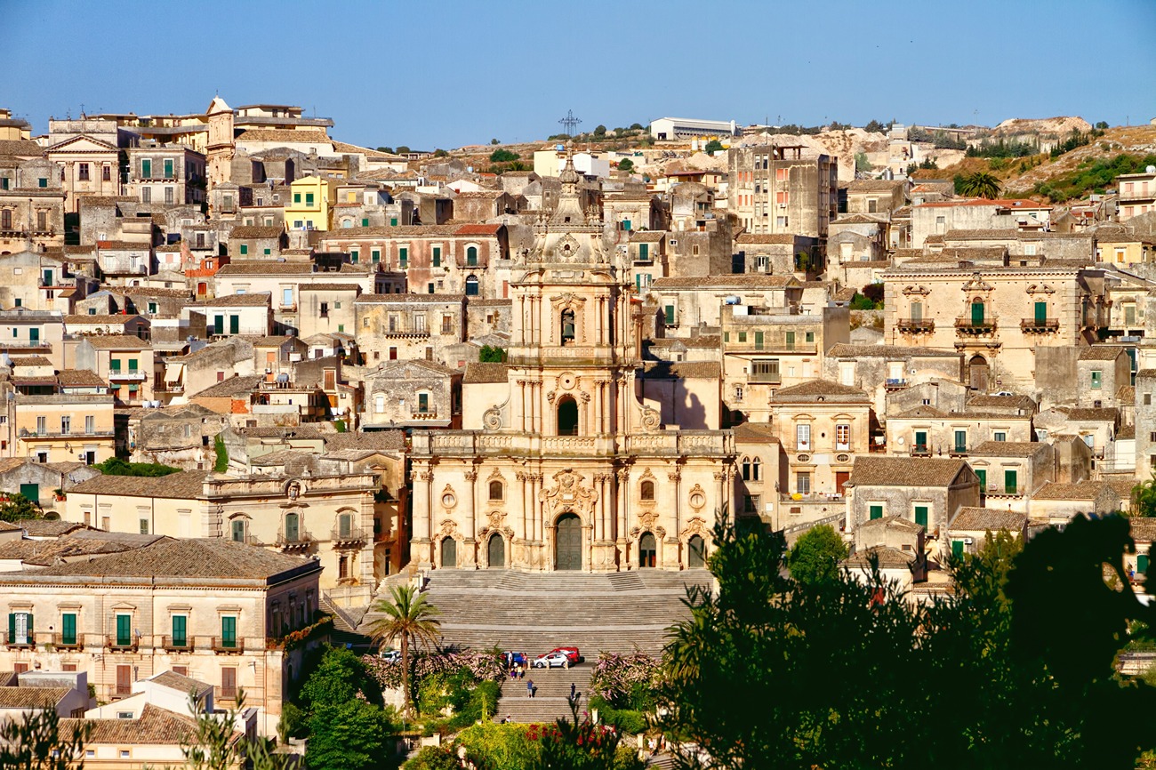A tan colour church amid many tan colour houses in Sicily Italy