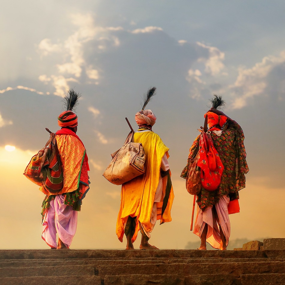 Three well dressed mean in front of a cloudy sunset in Inida