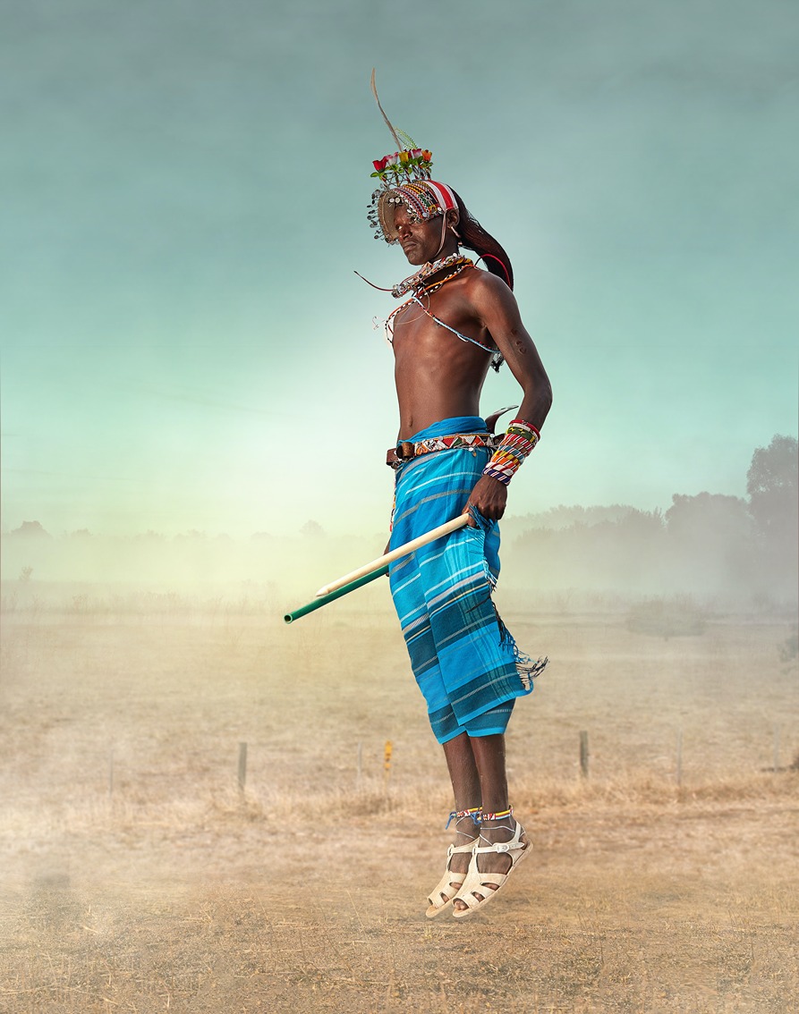 A massai man in blue sarong and traditional beads jumps high in a cultural show in kenya doing wtn's Kenya safari for women