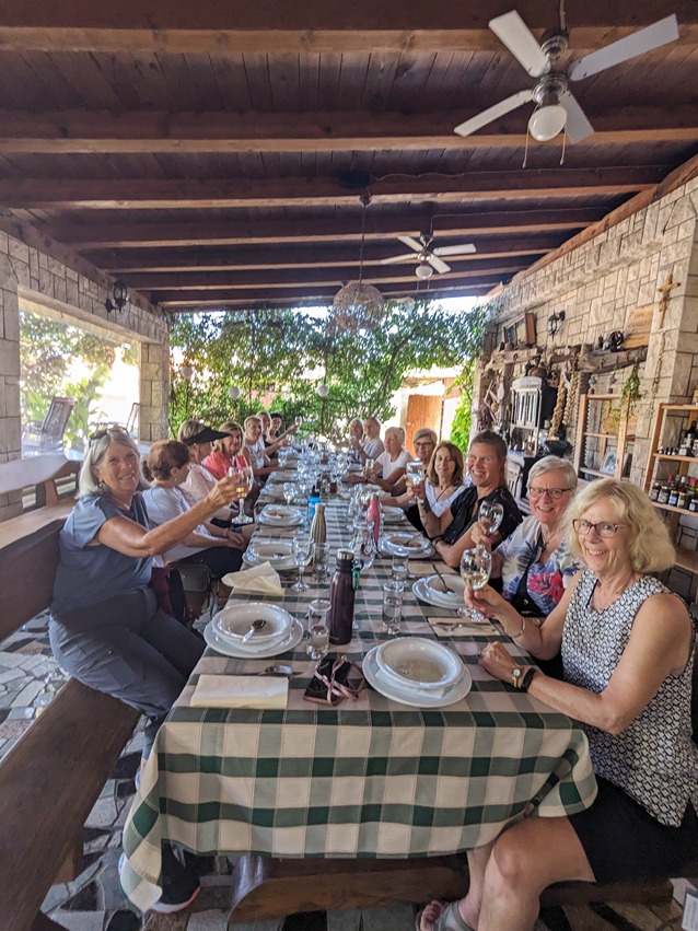 A group of smiling female travellers cheers around a dining table at a local farm in beautiful Croatia during Womens Travel Network's Croatia tour for women